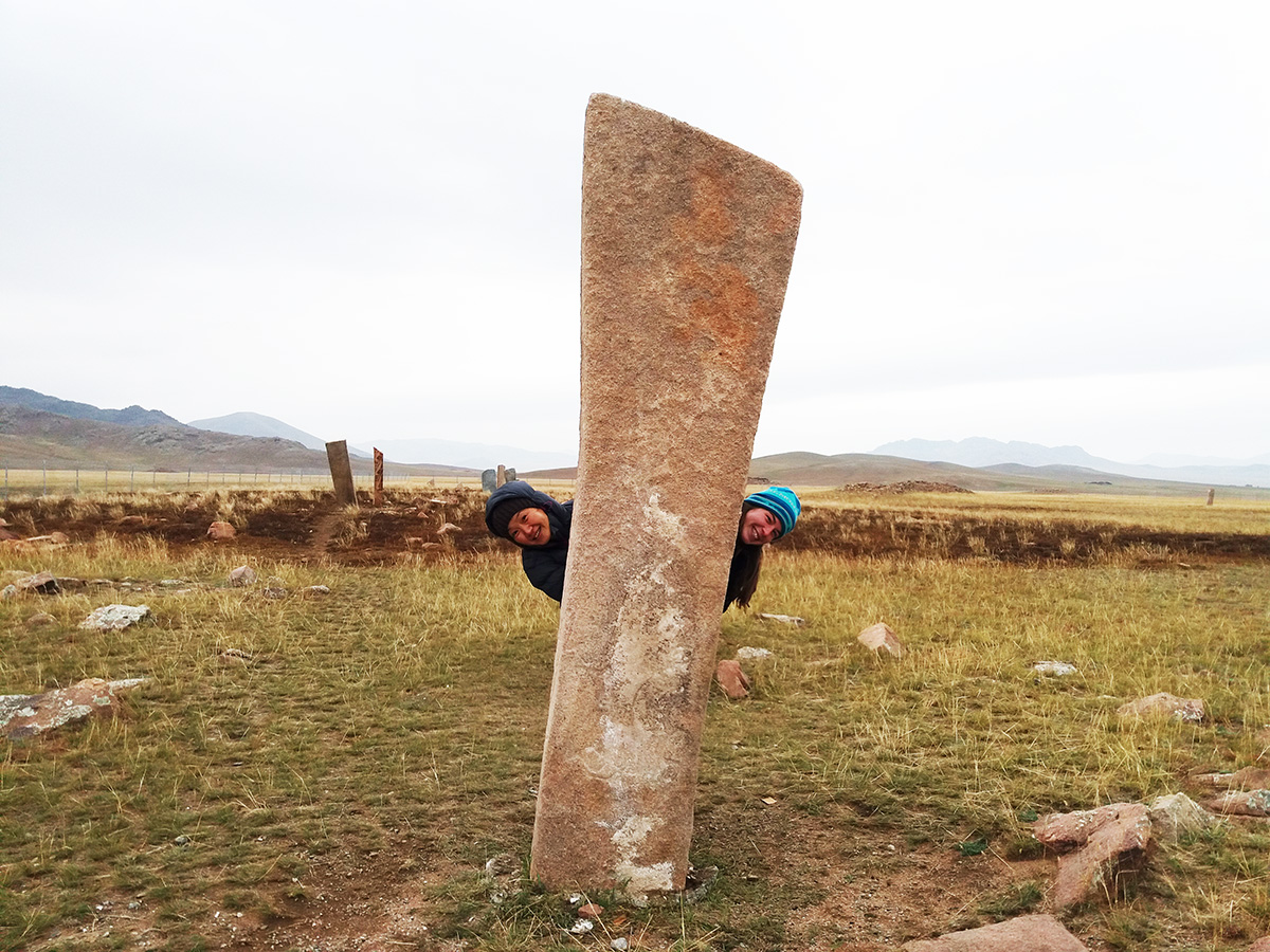 Travelers exploring ancient deer-stones on the Mongolian steppe